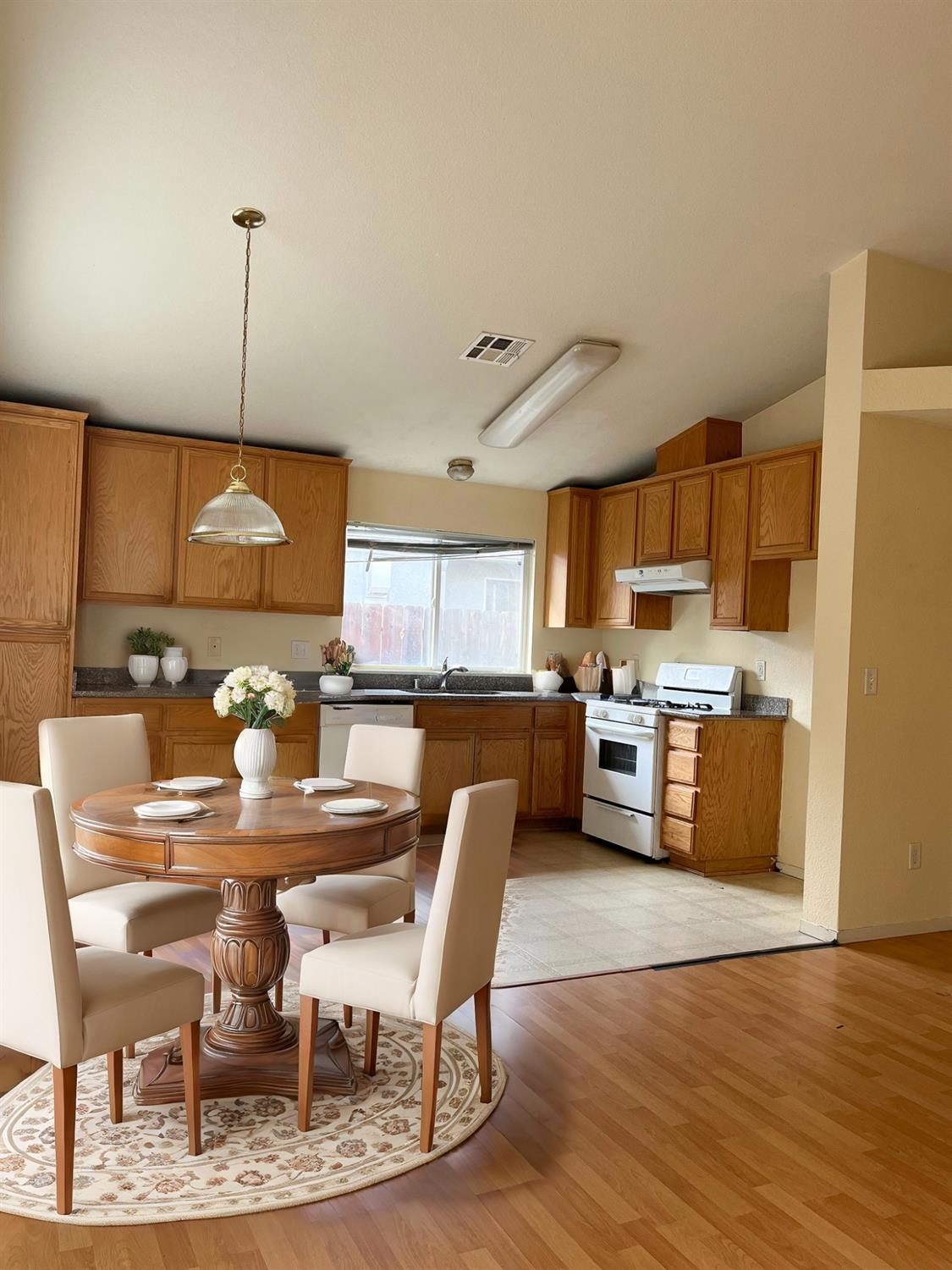 a kitchen with stainless steel appliances kitchen island granite countertop a dining table chairs and a refrigerator