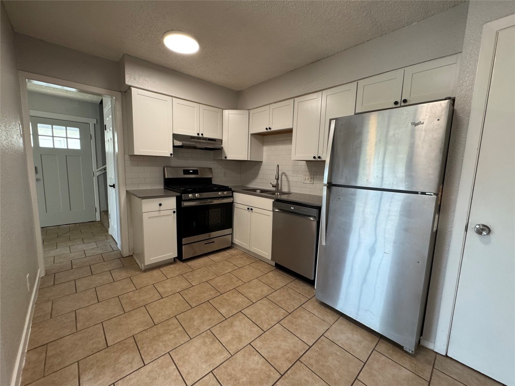 a kitchen with stainless steel appliances granite countertop a refrigerator and a stove top oven