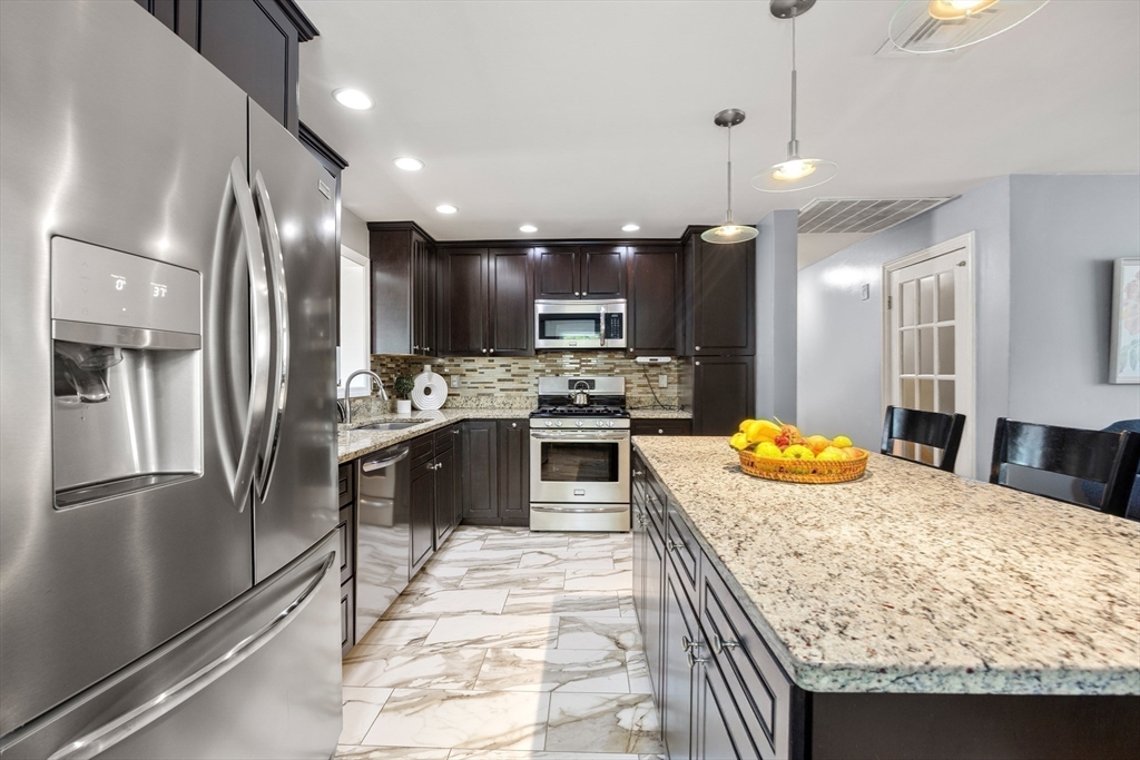 a kitchen with stainless steel appliances granite countertop a sink a stove and a refrigerator