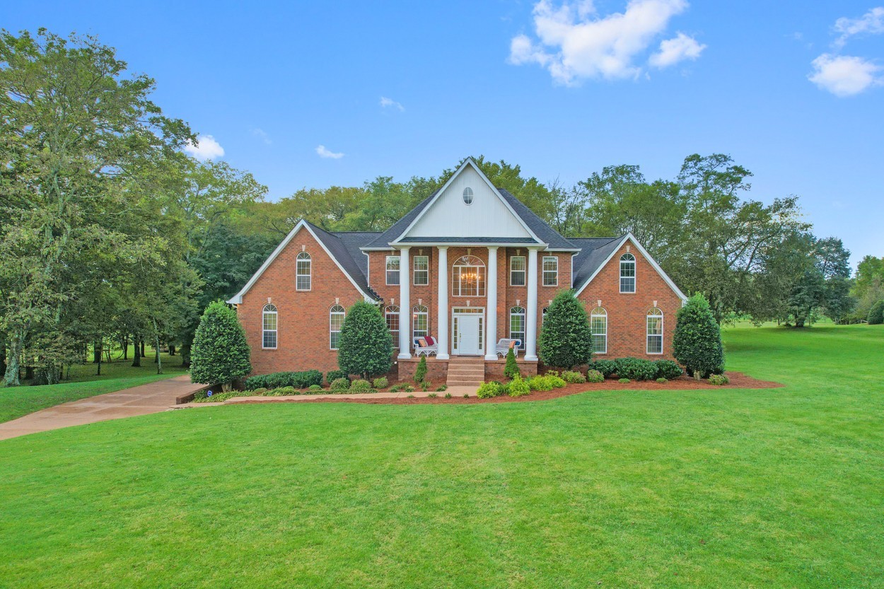 a front view of a house with a yard and trees