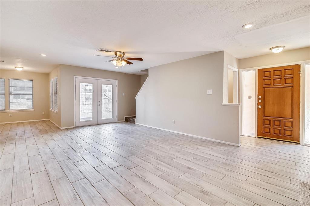 a view of an empty room with window and wooden floor