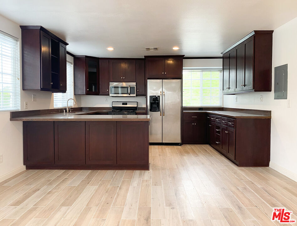 a kitchen with stainless steel appliances kitchen island granite countertop a refrigerator and a sink