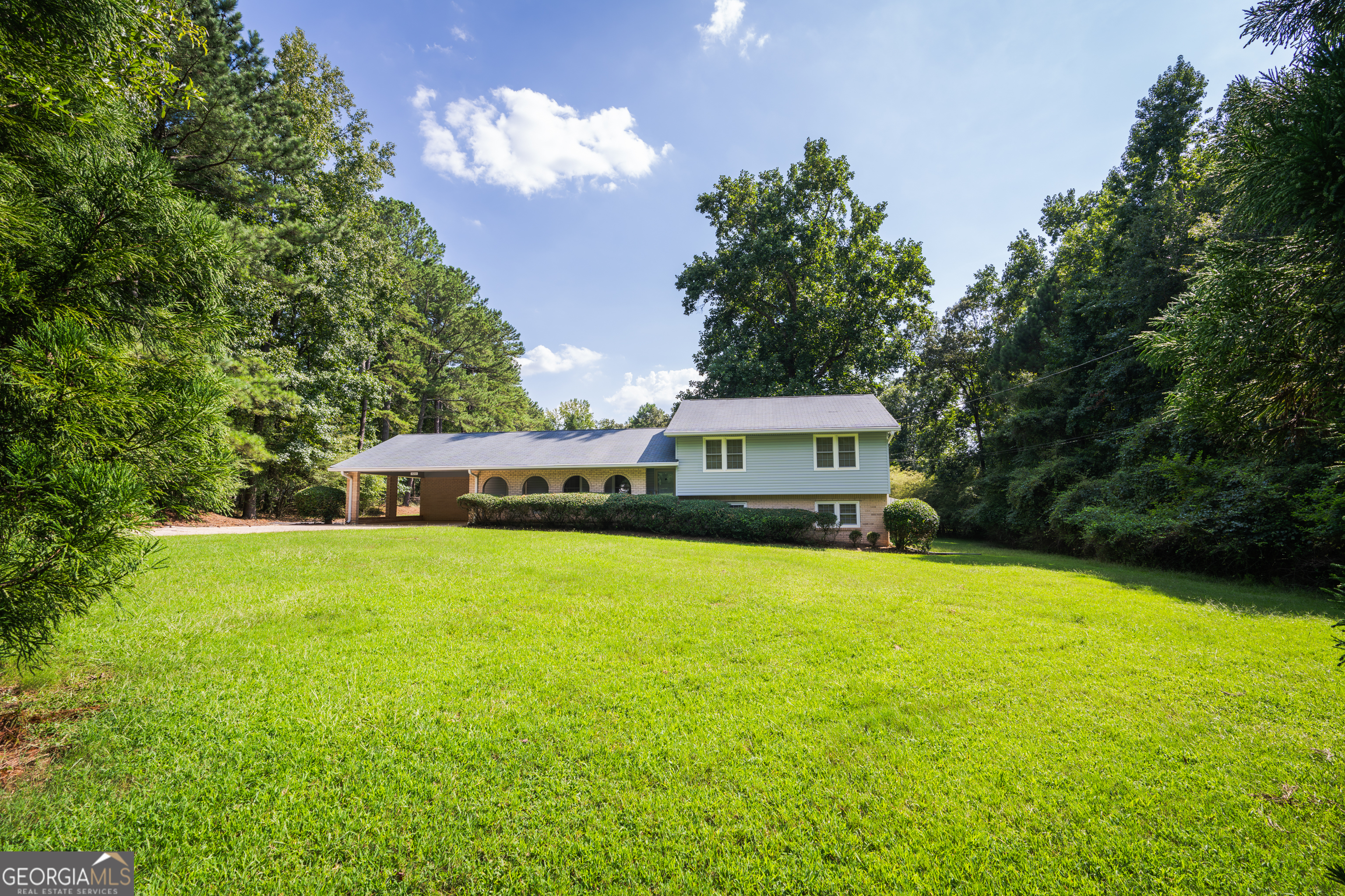 a front view of a house with a garden and trees