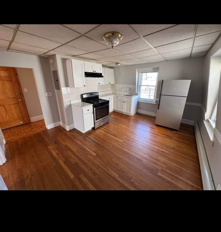 a view of kitchen with microwave a stove and wooden floor