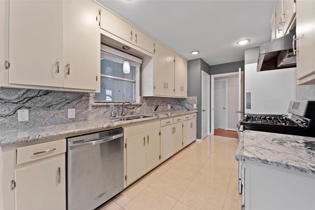 a kitchen with granite countertop a sink stainless steel appliances and white cabinets