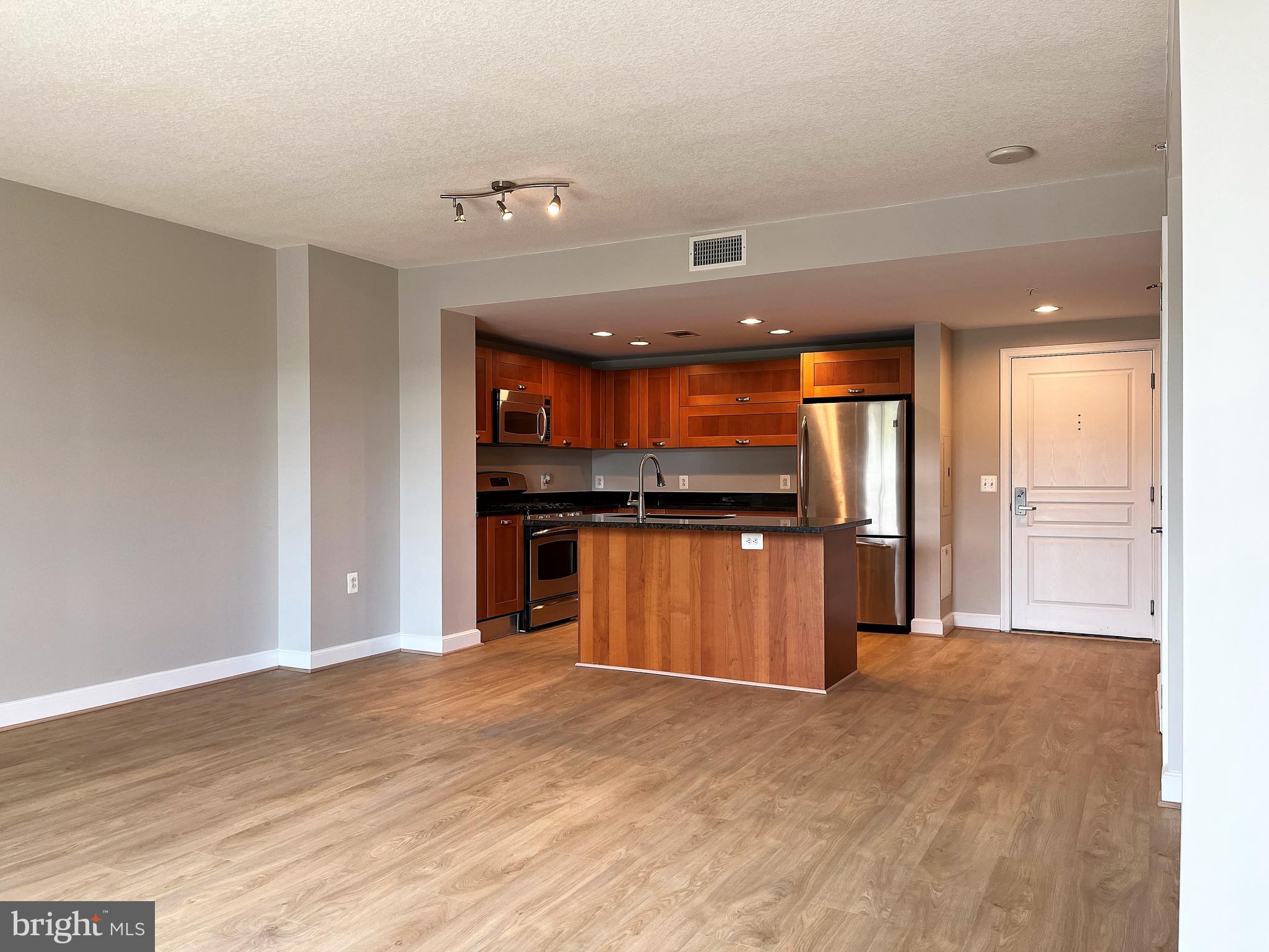 a kitchen with stainless steel appliances kitchen island granite countertop a refrigerator and a sink