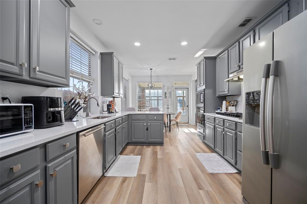 a large kitchen with stainless steel appliances lots of counter space and wooden floor