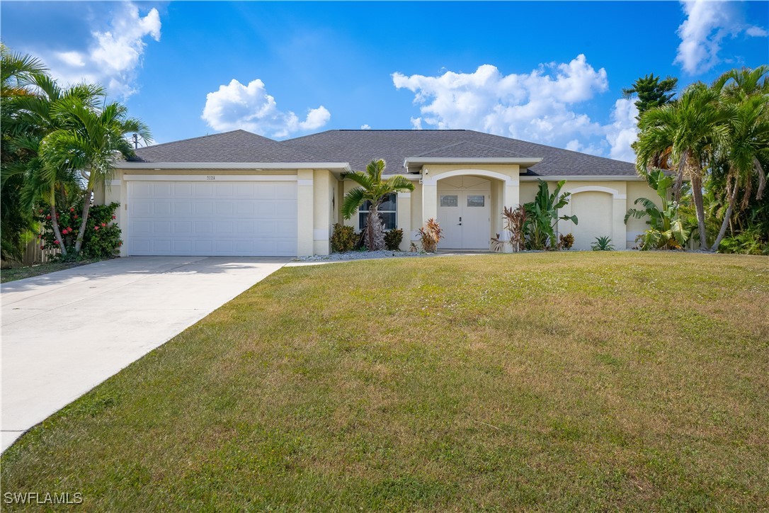 a front view of house with yard and trees in the background