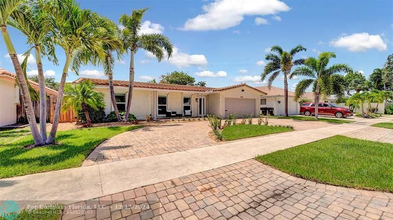 a view of multiple houses with a yard and palm trees