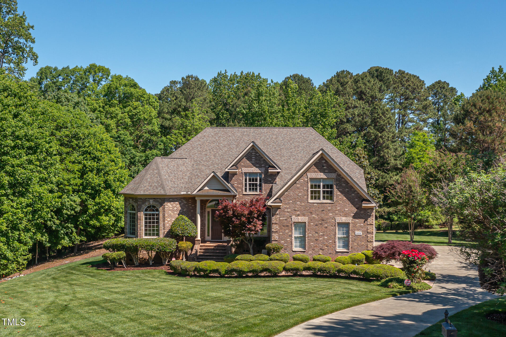 a front view of a house with a garden and trees