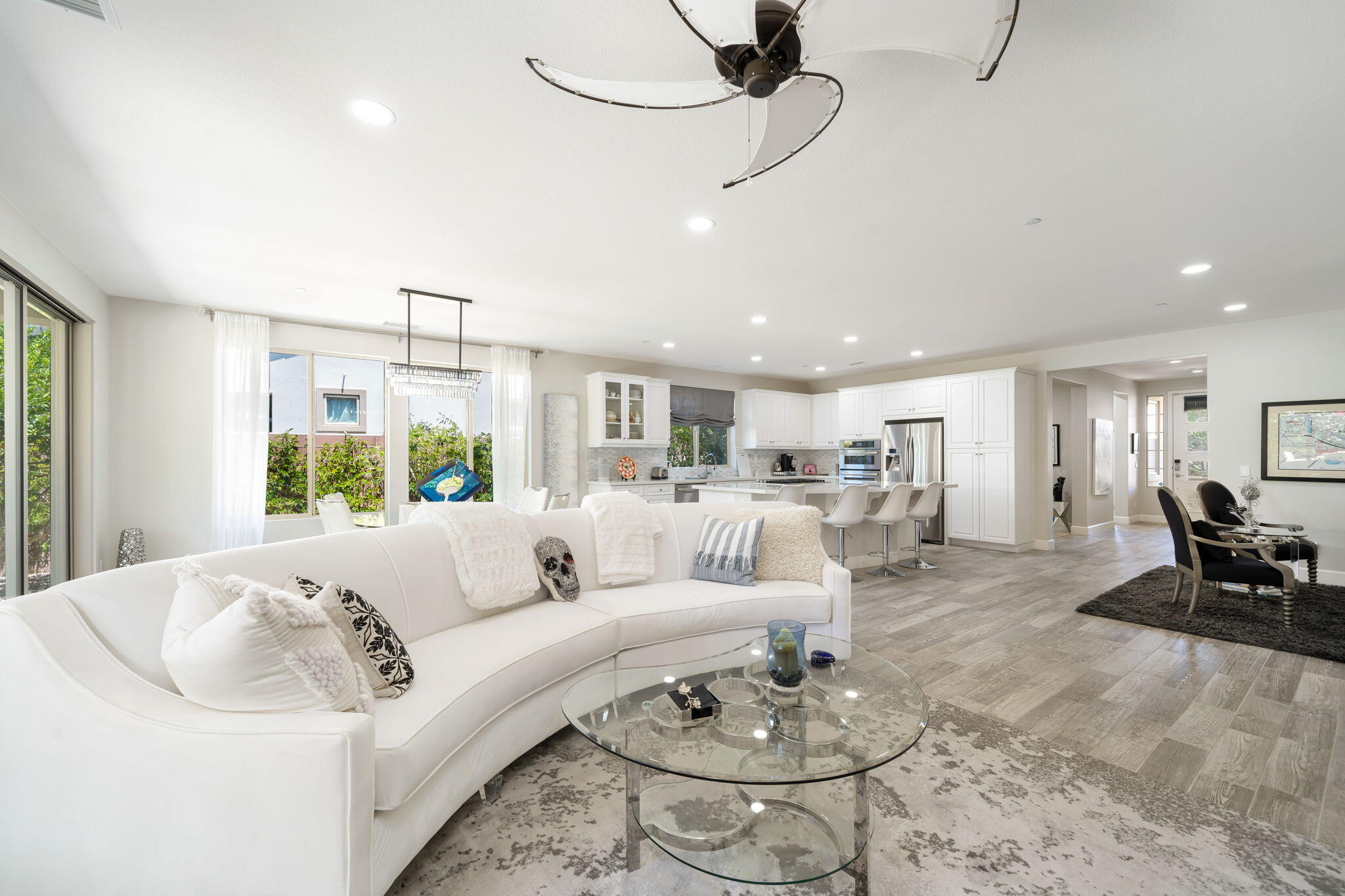 a living room with furniture kitchen view and a chandelier