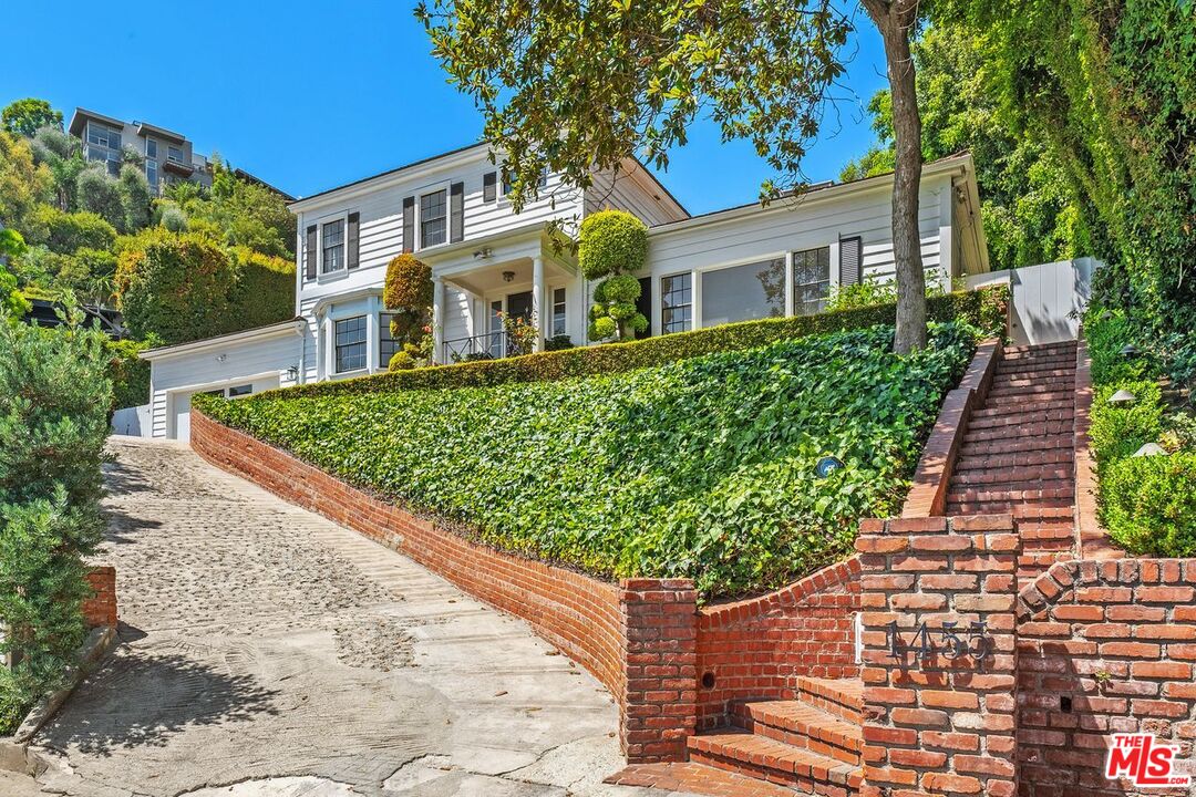 a front view of a house with a yard and potted plants