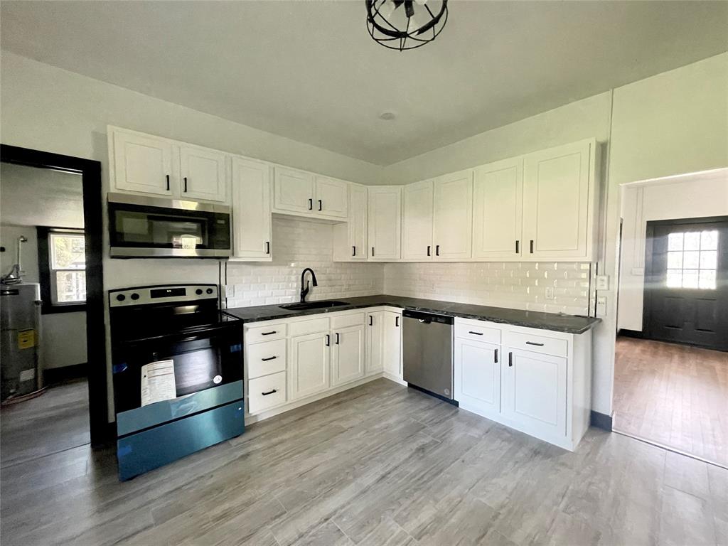 a kitchen with granite countertop white cabinets and stainless steel appliances