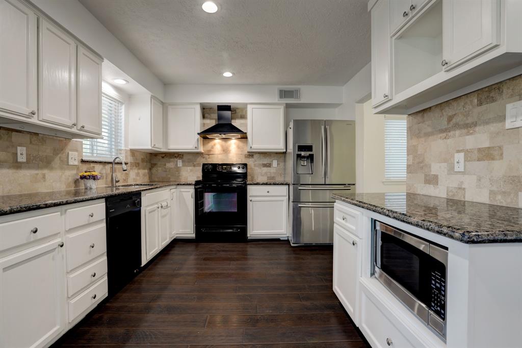 a kitchen with granite countertop a sink cabinets stainless steel appliances and a counter space