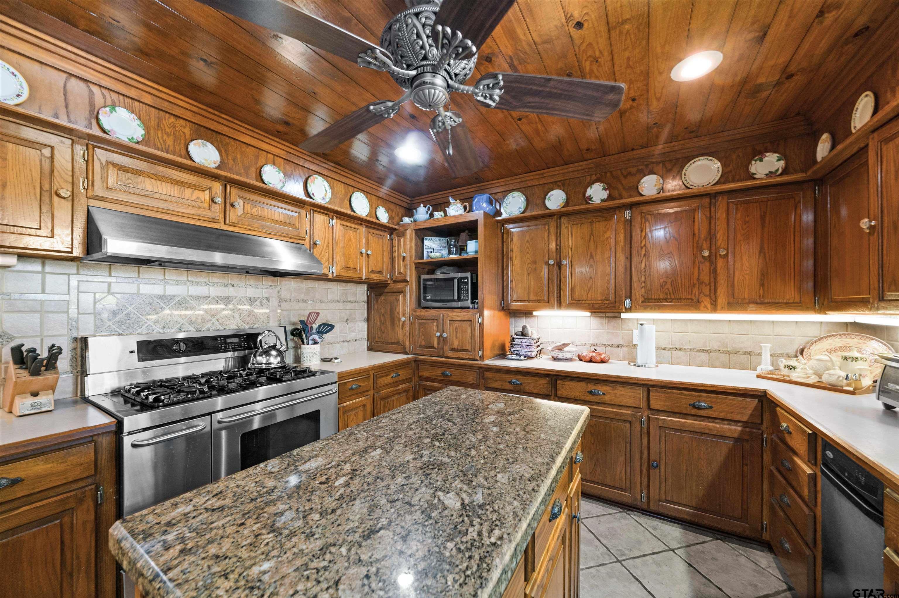 a kitchen with stainless steel appliances kitchen island granite countertop a sink and cabinets