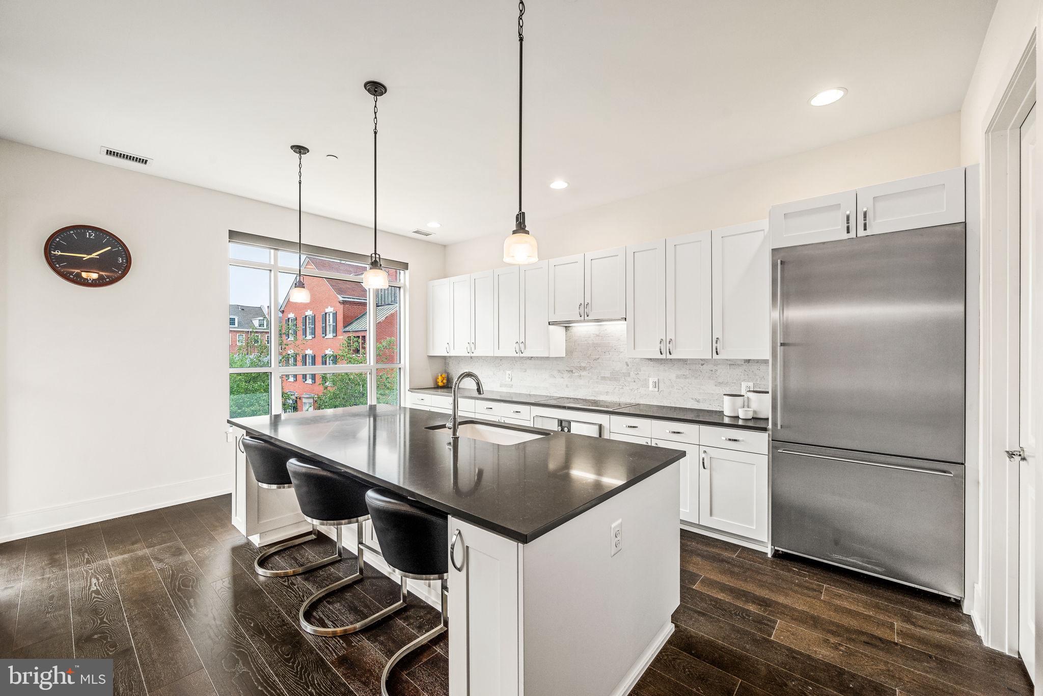 a kitchen with kitchen island a counter top a stove a refrigerator and a wooden floor