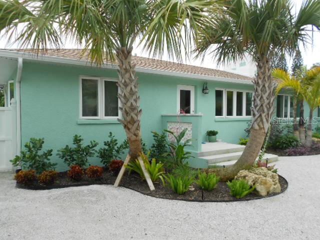 a view of a house with a small yard and palm trees