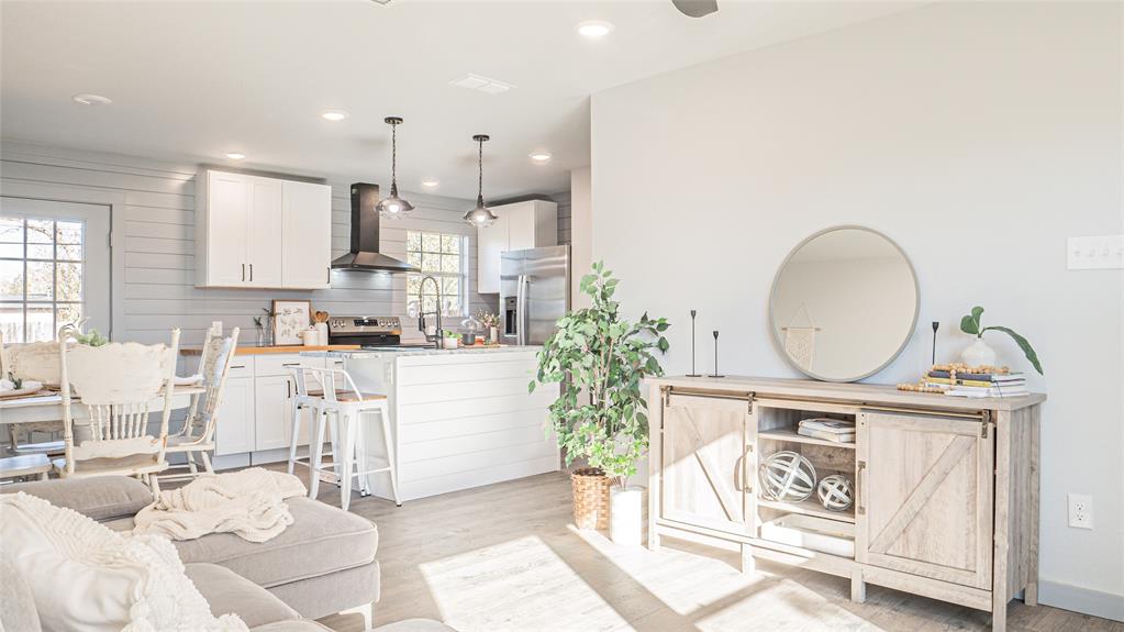 a open kitchen with granite countertop a stove a sink and a dining table with wooden floor