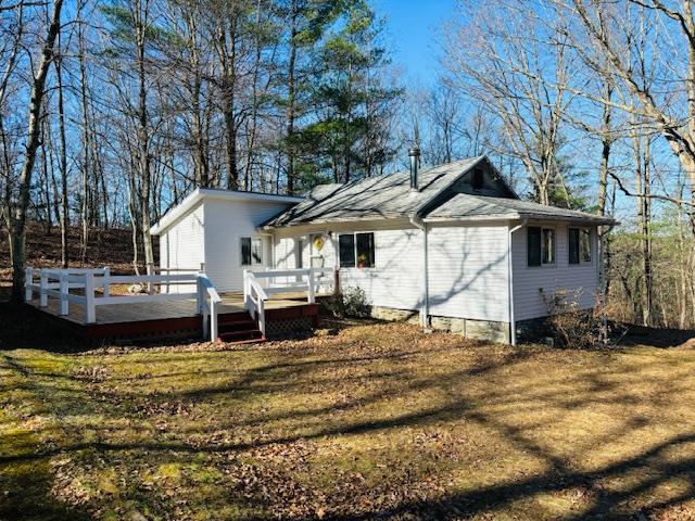 Back of house with a wooden deck and a yard