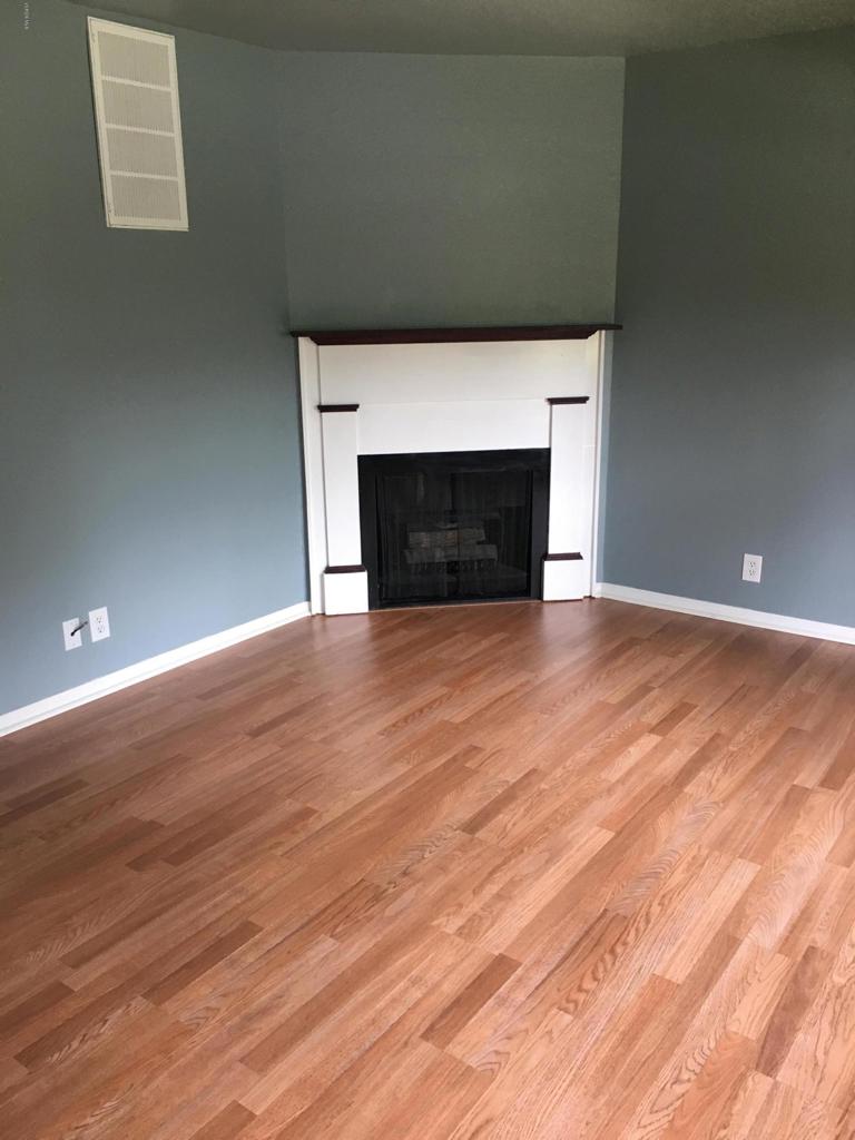 a view of empty room with wooden floor and fireplace