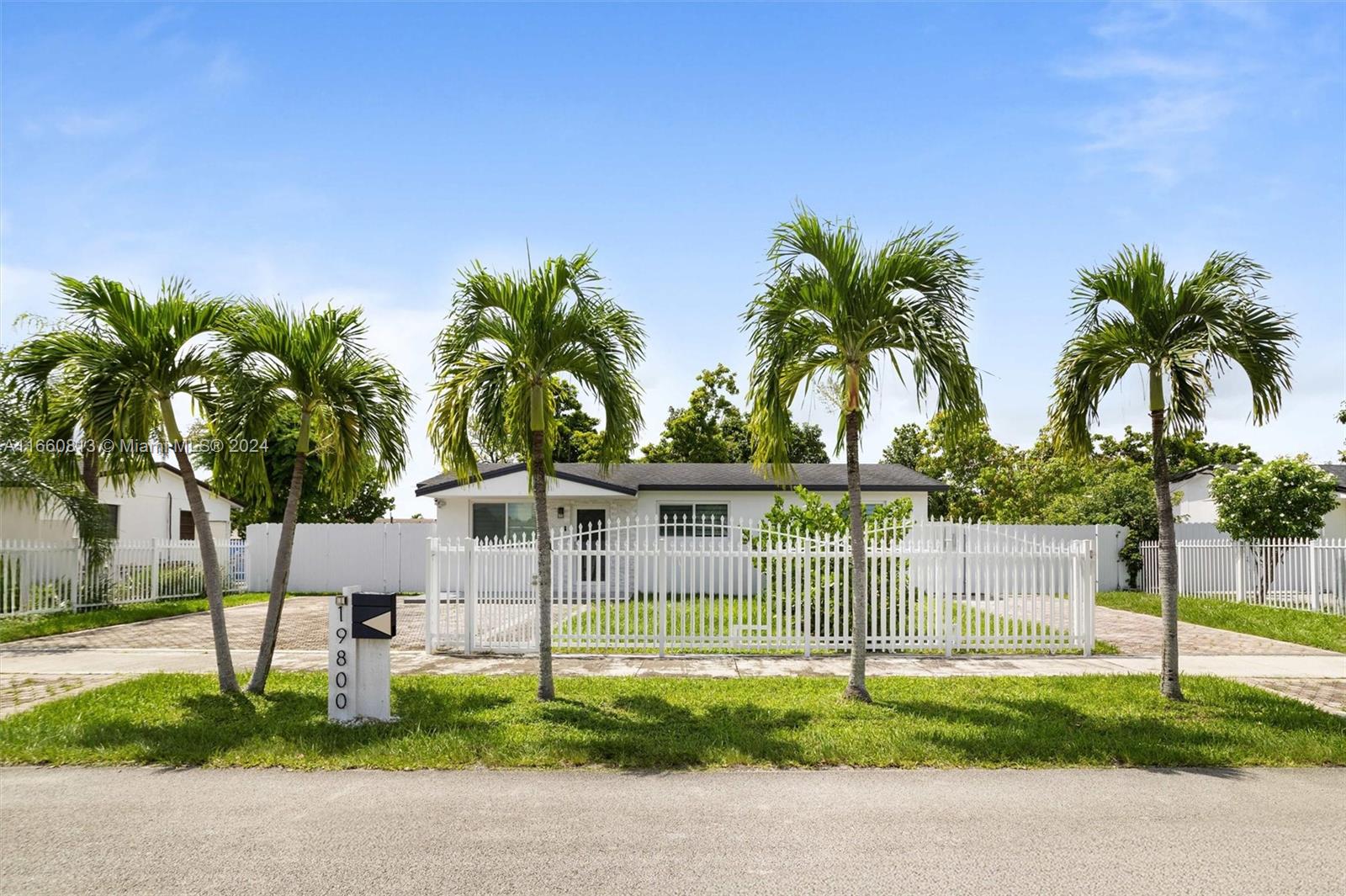 a palm tree sitting in front of a house with a garden