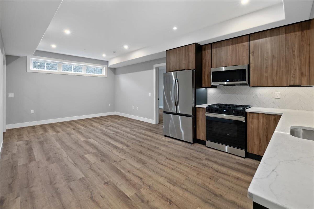 a kitchen with granite countertop wooden floors stainless steel appliances and a sink