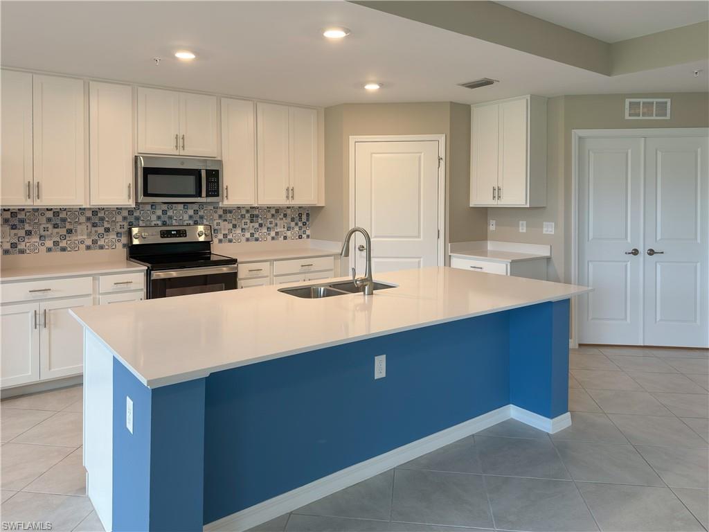 a kitchen with sink a microwave and cabinets