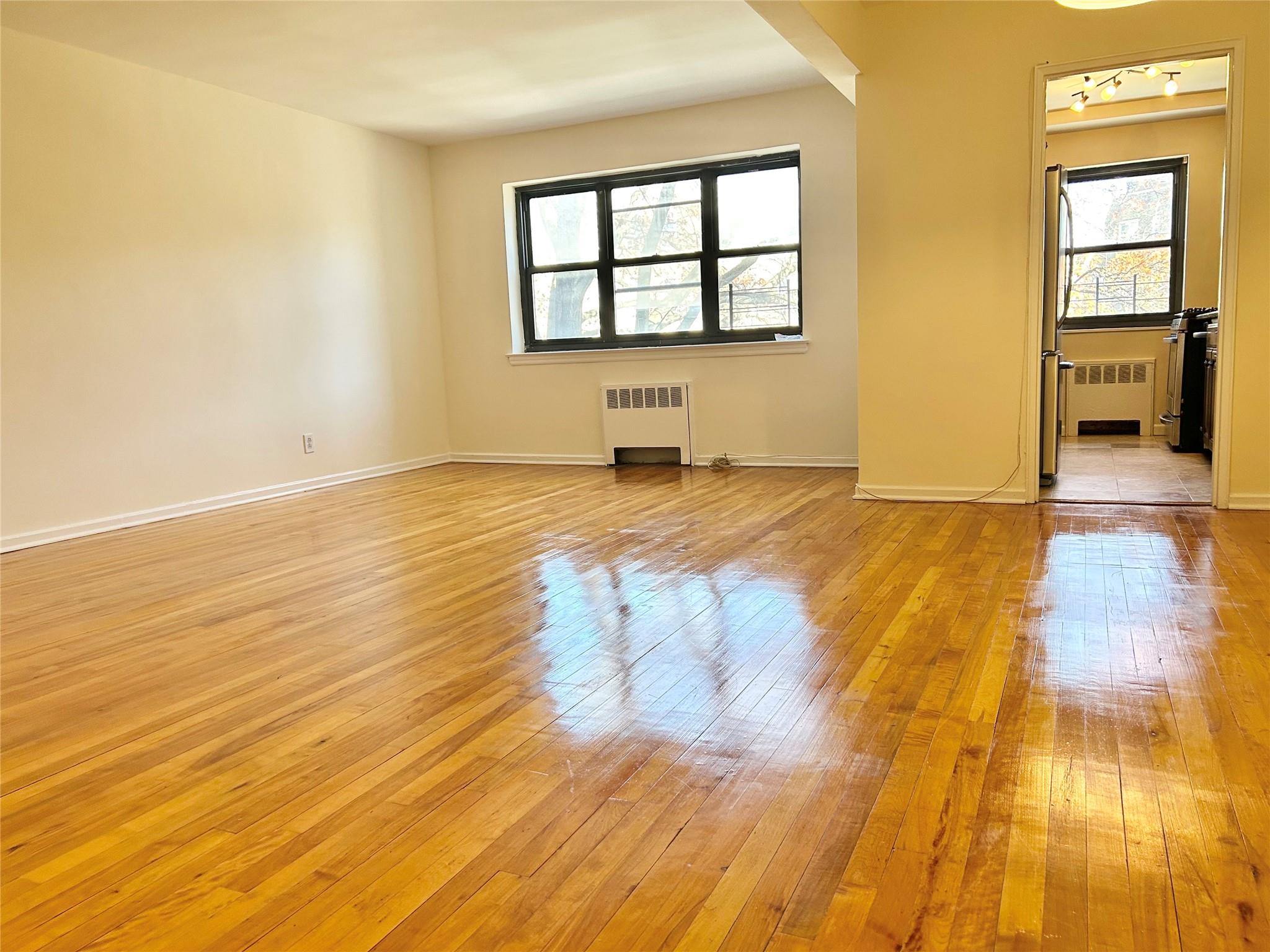 a view of empty room with wooden floor and windows