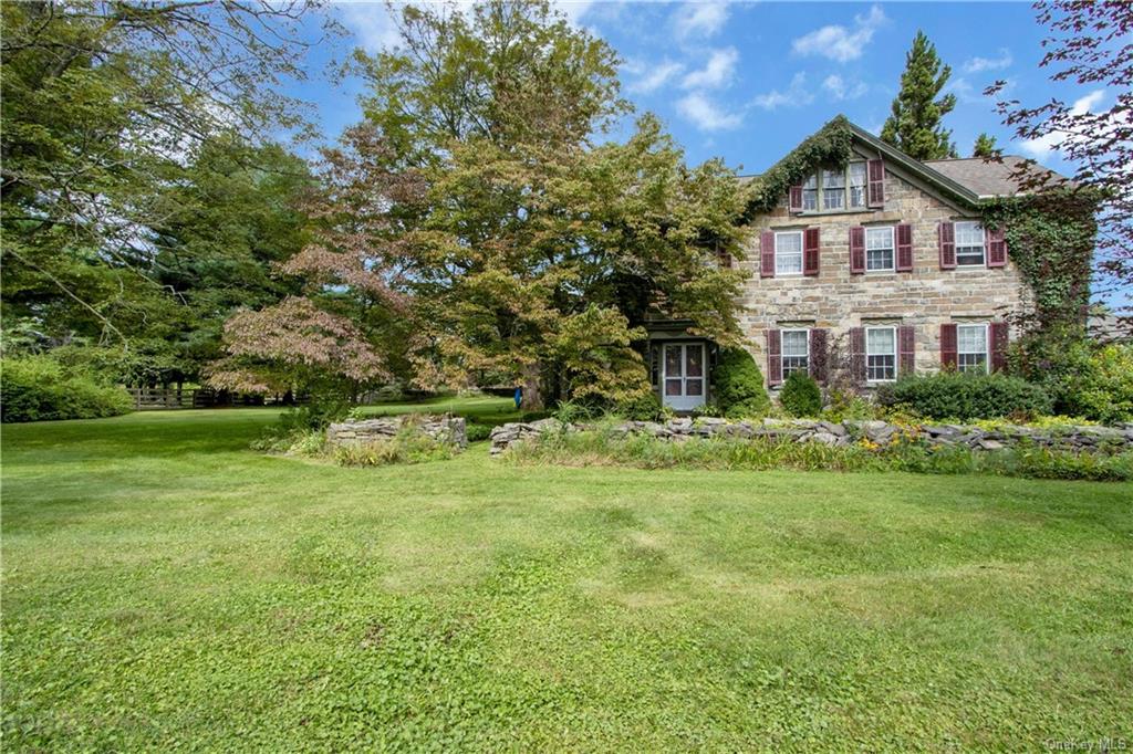 a view of a big house with a big yard and large trees