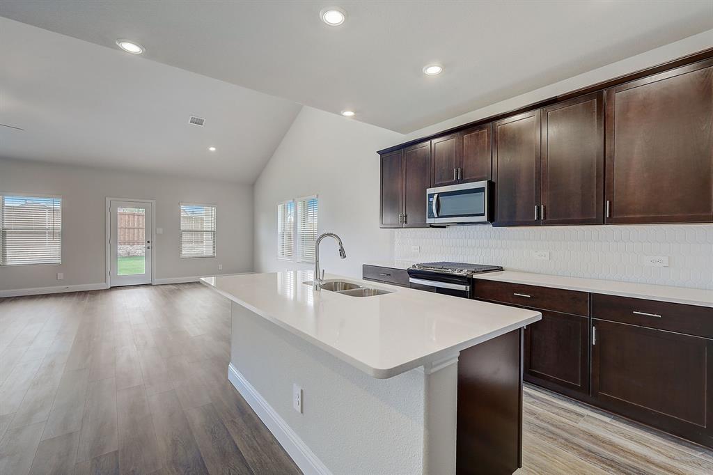 a kitchen with a sink and a stove top oven with wooden floor