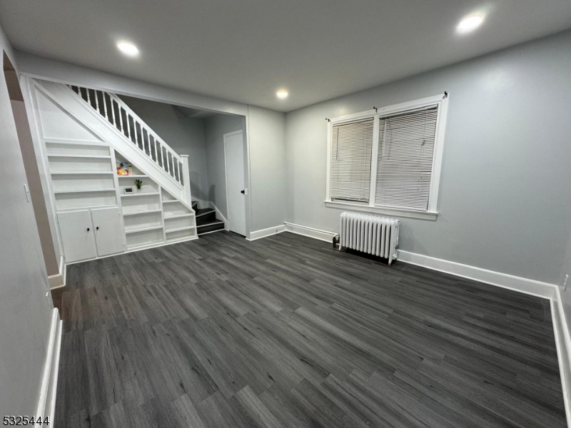 a view of an empty room with wooden floor and stairs