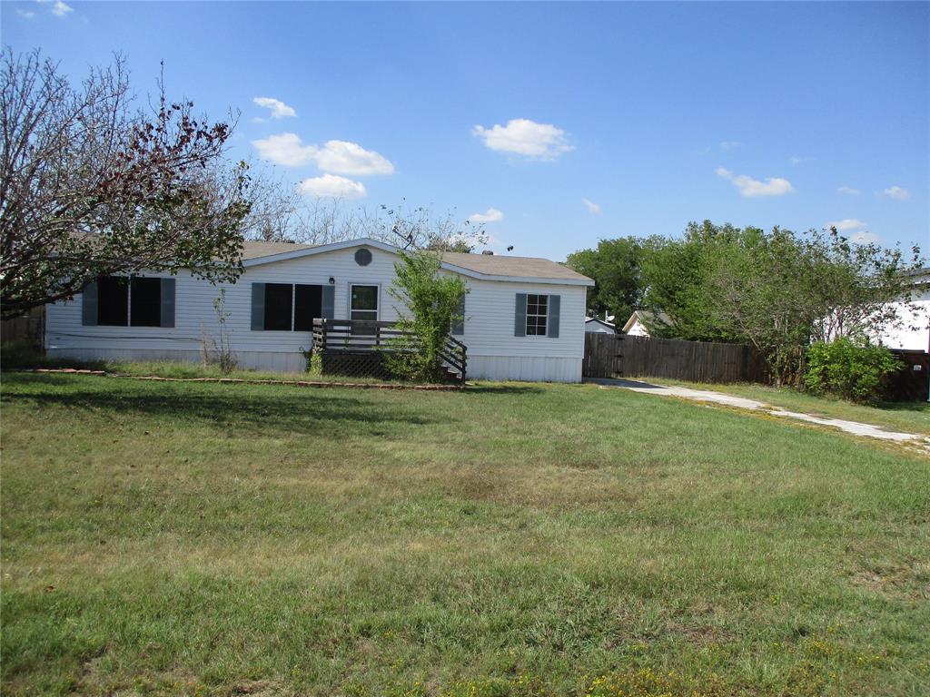 a front view of house with yard and trees in the background