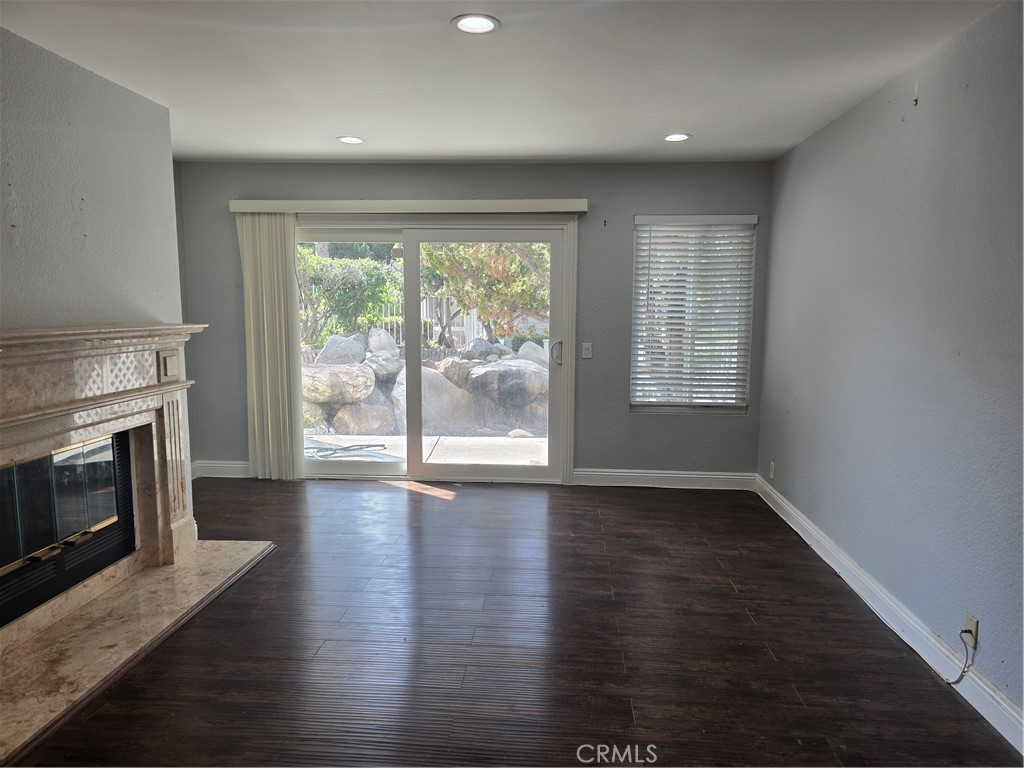 an empty room with wooden floor fireplace and windows