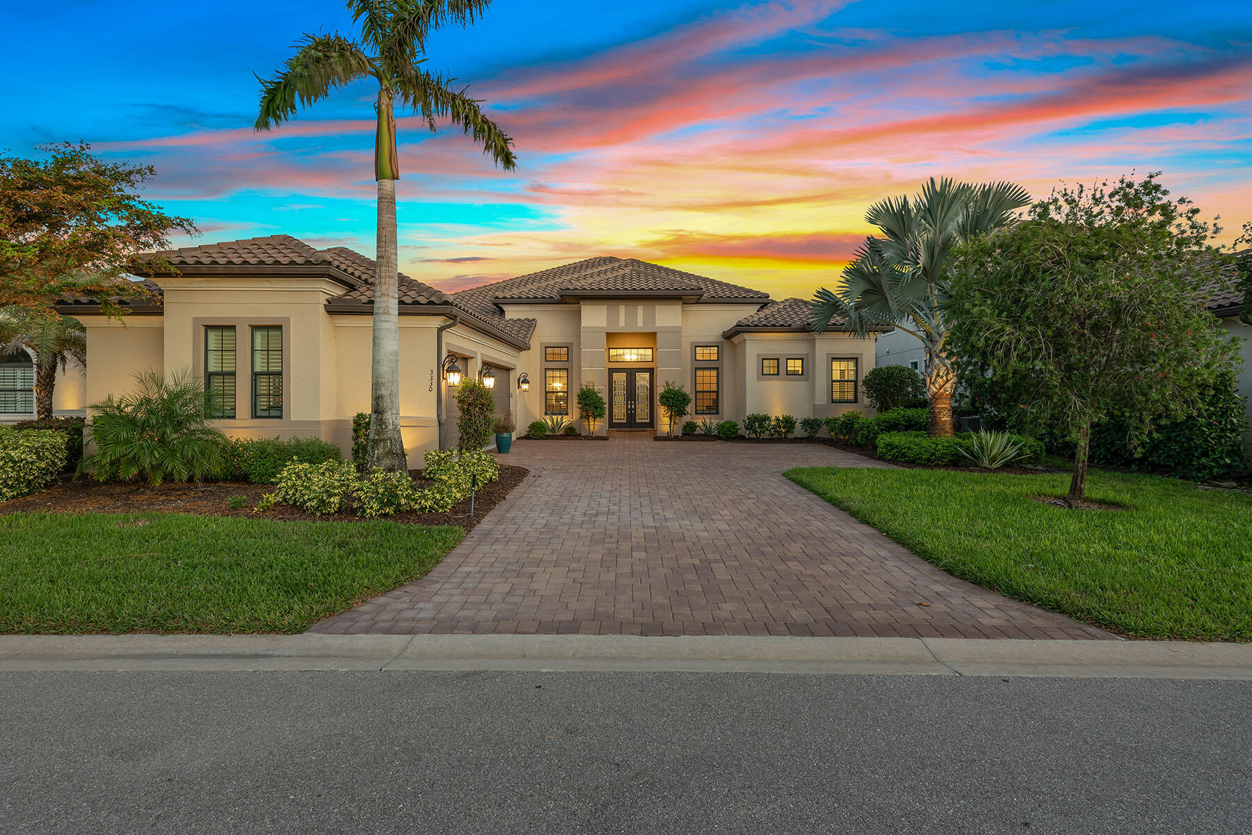 a view of a white house with a small yard and palm trees