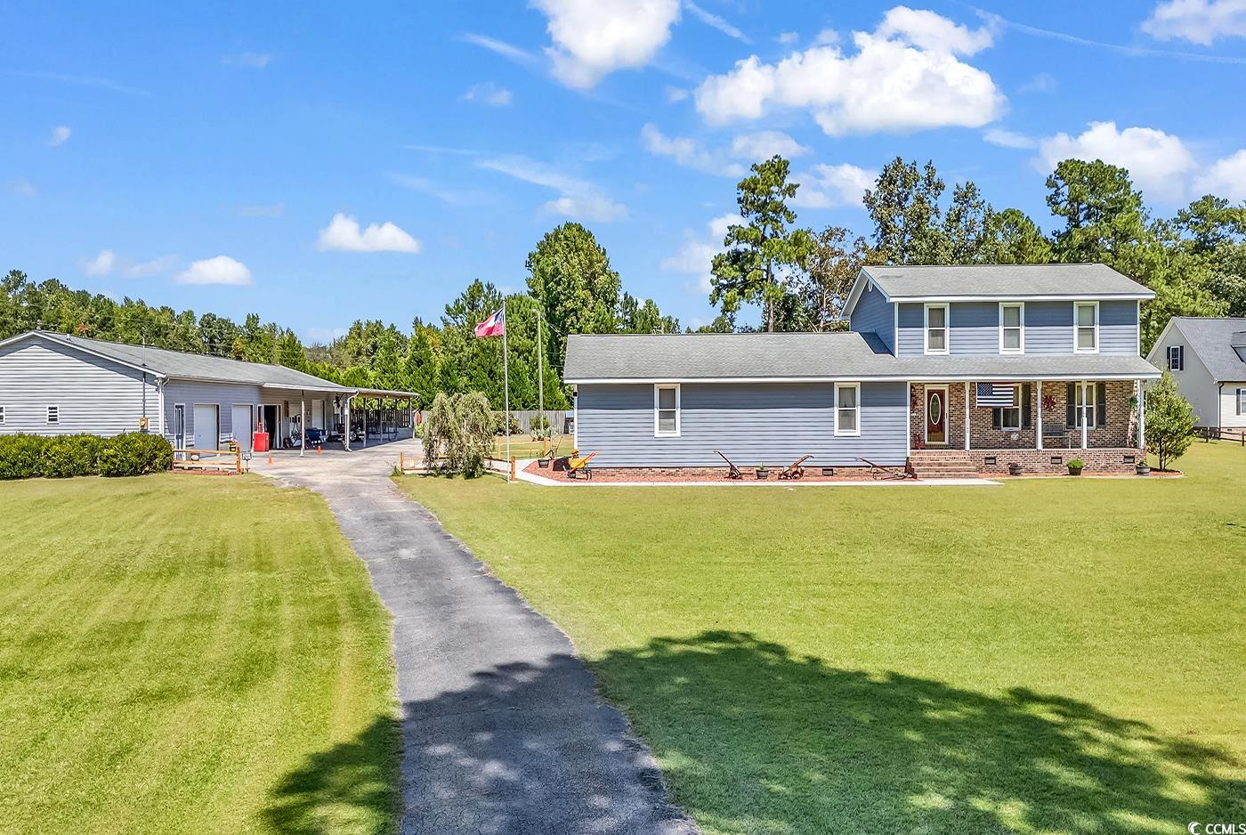 View of front of home with a front yard and covere