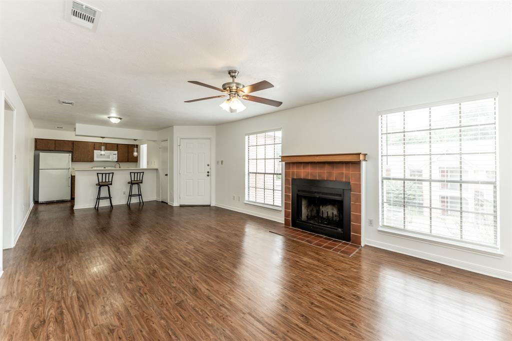 a view of a livingroom with a fireplace a ceiling fan and windows