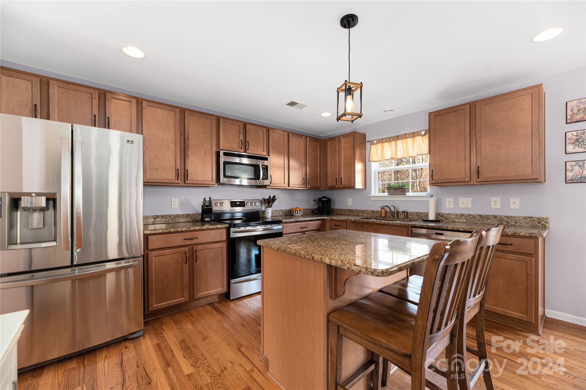 a kitchen with stainless steel appliances granite countertop a stove a refrigerator a sink dishwasher a dining table and chairs with wooden floor