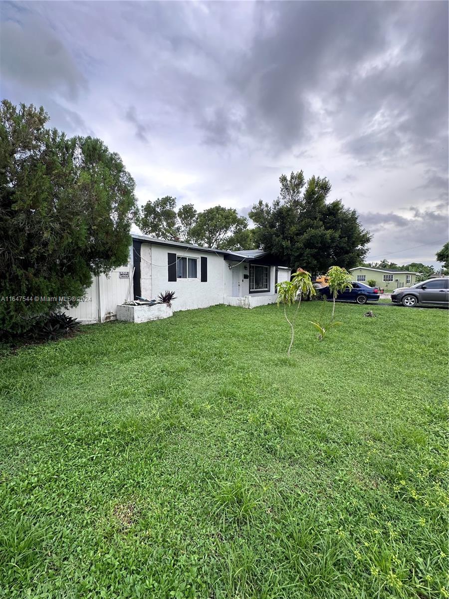 a view of a house with a big yard and a large tree