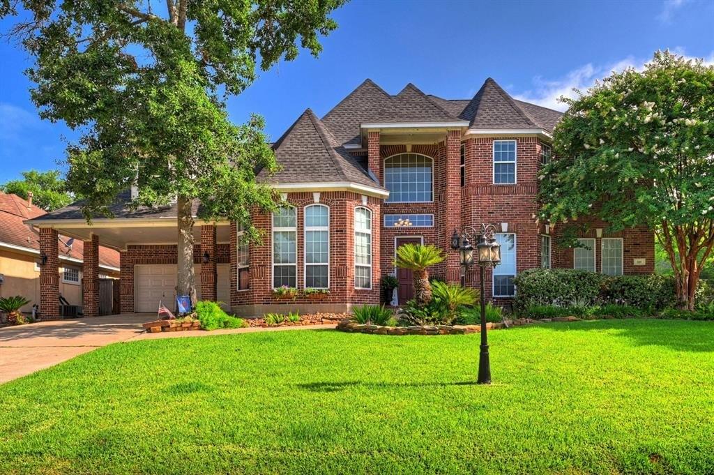 a front view of a house with a yard and large tree