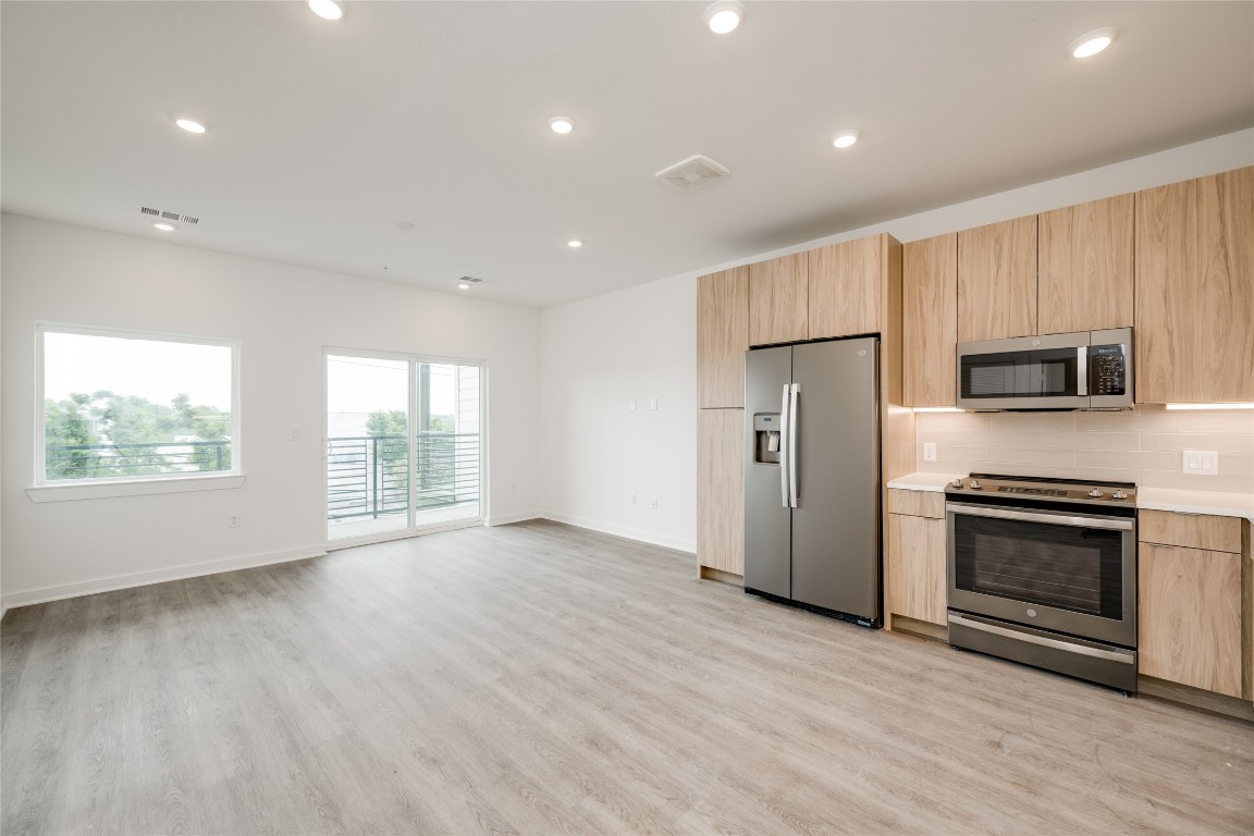 a view of kitchen with stainless steel appliances granite countertop a stove a sink dishwasher a microwave oven with cabinets and wooden floor