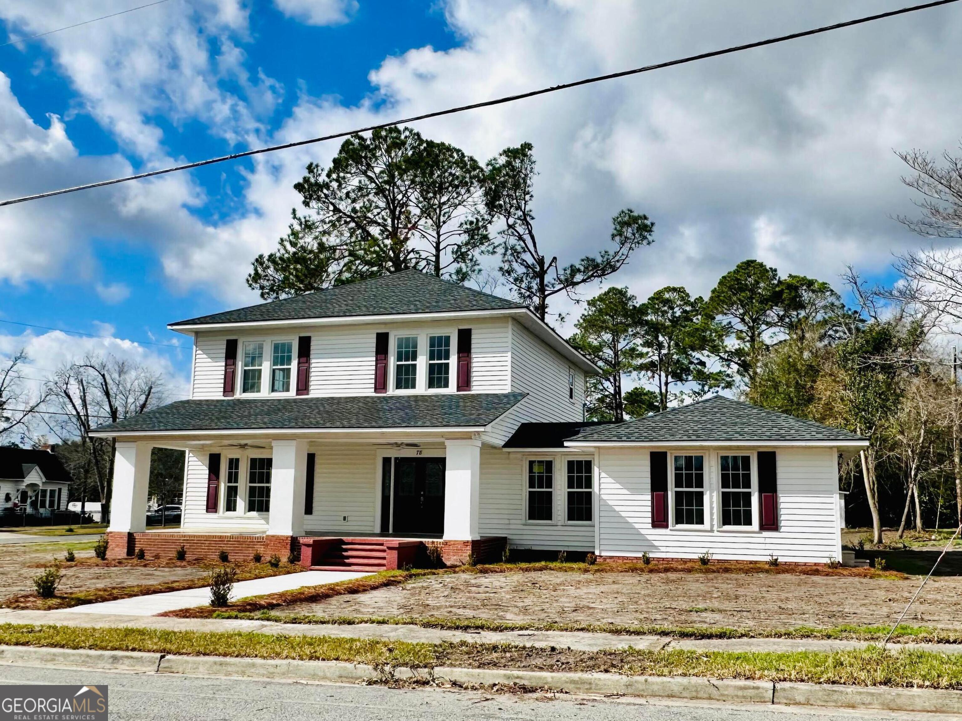 a front view of a house with a yard and a tree