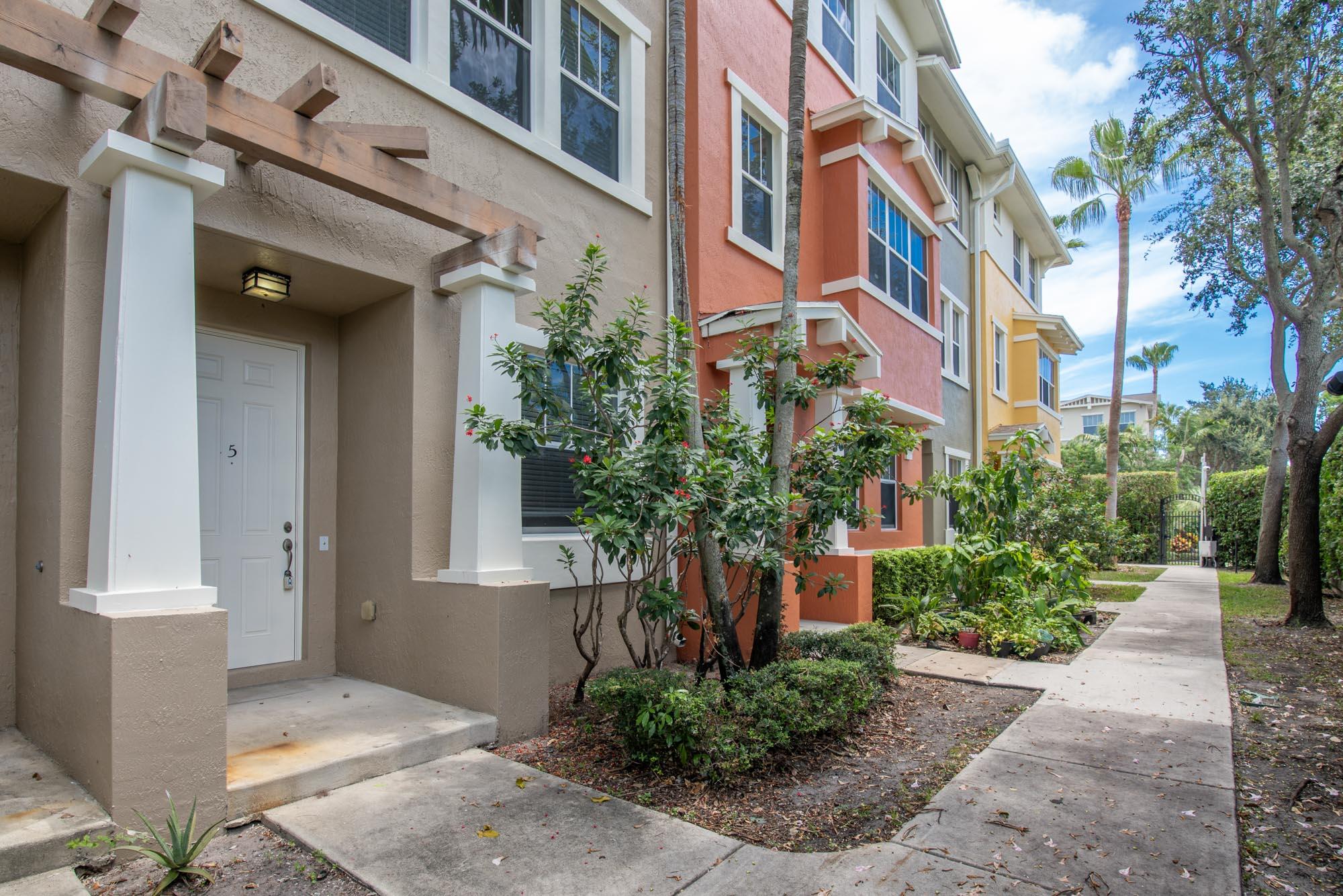 a front view of a multi story residential apartment building with yard and green space