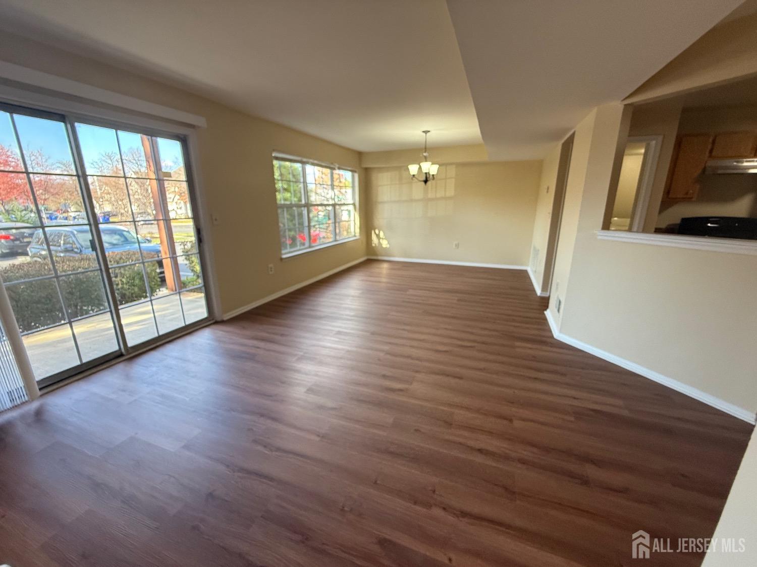 a view of an empty room with glass door and wooden floor