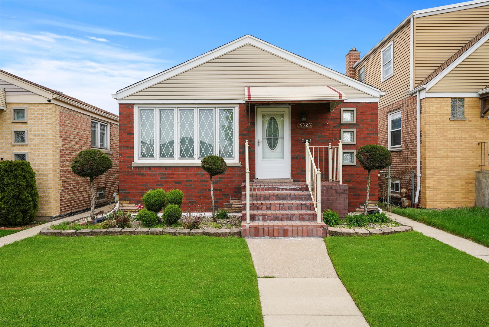 a front view of a house with a yard and potted plants