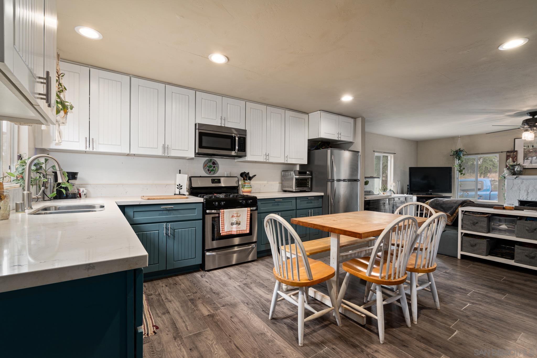 a kitchen with kitchen island granite countertop wooden floors a sink and appliances