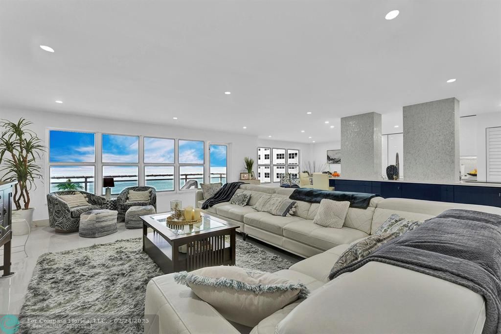 a living room with furniture kitchen view and large windows