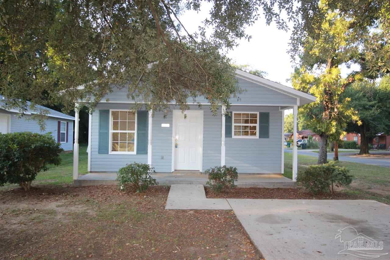 a front view of a house with a yard and tree