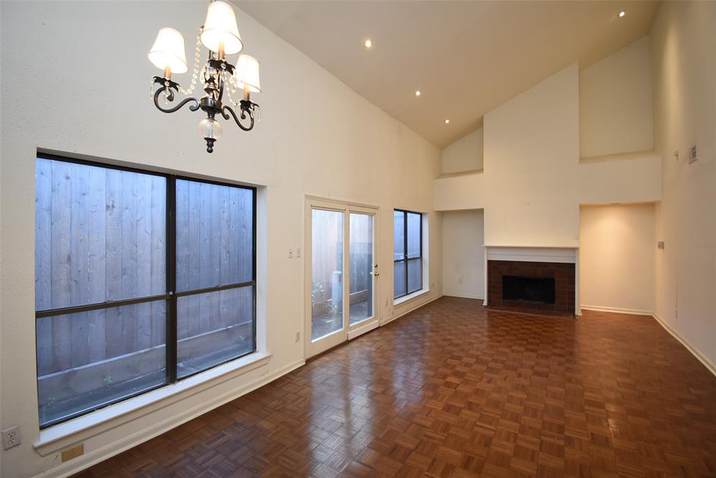 a view of a livingroom with a fireplace a chandelier a ceiling fan and windows