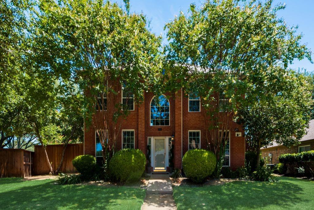 a view of a brick house with a large windows and a large tree