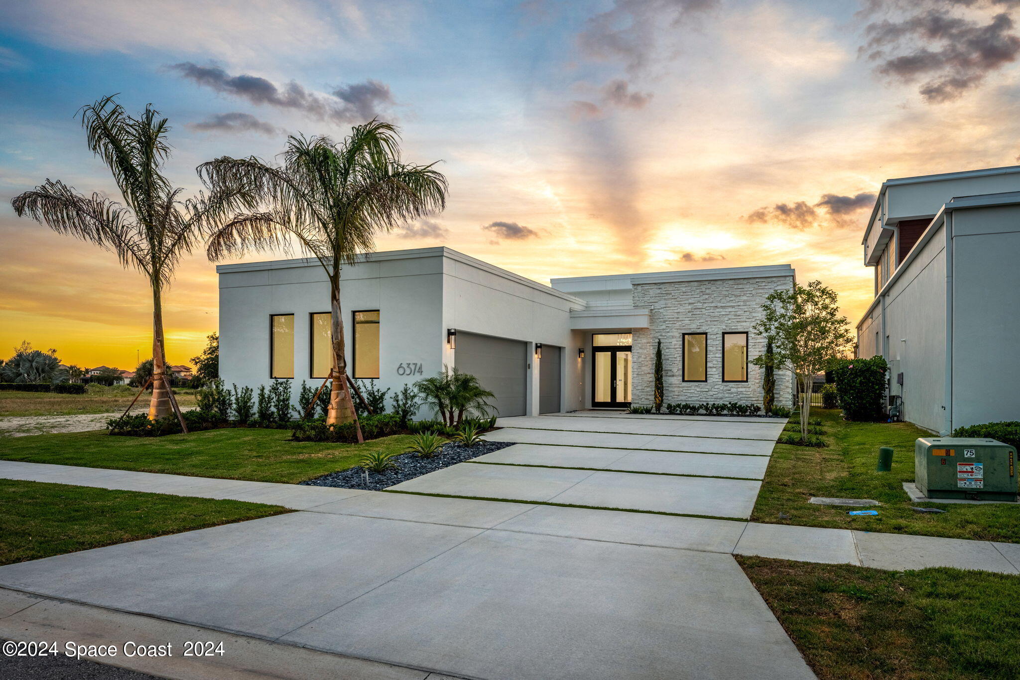 a front view of a house with a garden and palm trees